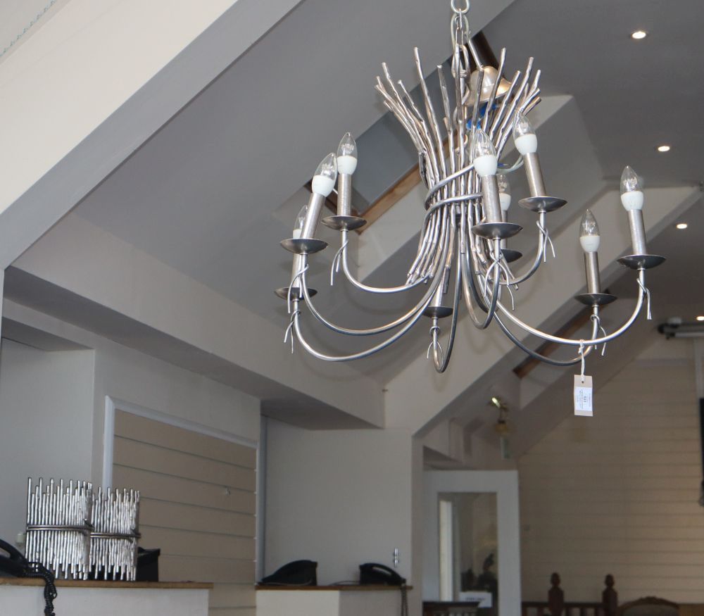 A modern silvered metal nine-light chandelier in the form of a tied bundle of twigs and six wall lights to match